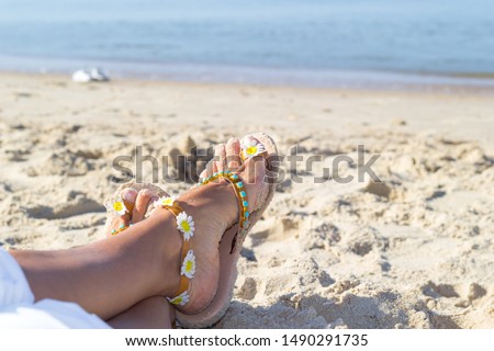 Leisure at the sea. Female feets lay on golden sand near seashore. Copy space.