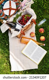 Leisure And Summer Concept - Close Up Of Picnic Basket With Food And Drinks And Book On Blanket On Grass