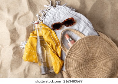 Leisure And Summer Holidays Concept - Sunscreen In Bag, Sunglasses, Bottle Of Water, Pareo And Beach Blanket On Sand