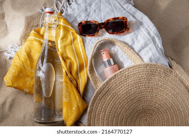 Leisure And Summer Holidays Concept - Sunscreen In Bag, Sunglasses, Bottle Of Water, Pareo And Beach Blanket On Sand