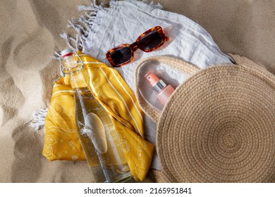 Leisure And Summer Holidays Concept - Sunscreen In Bag, Sunglasses, Bottle Of Water, Pareo And Beach Blanket On Sand