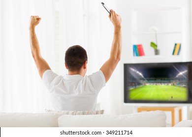 Leisure, Technology, Media, Sport And People Concept - Man Watching Football Game On Tv And Supporting Team At Home From Back