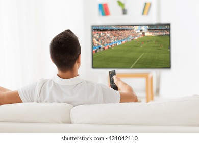 Leisure, Technology, Sport, Entertainment And People Concept - Man With Remote Control Watching Football Or Soccer Game On Tv At Home