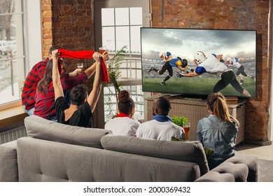 Leisure time. Excited, happy men and women, friends watching american football match, championship on the couch at home. Fans emotional cheering for favourite national team. Drinking beers. Sport, TV
