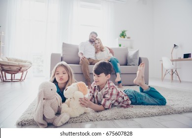 Leisure together. Happy family of four is enjoying at home, small kids are playing with toys, parents are on the sofa, hugging