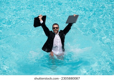 Leisure weekend and remote freelance work. Crazy comic business. Funny businessman in suit with laptop in swimming pool water. Remote summer work. Businessman relaxing in a swimming pool in a suit. - Powered by Shutterstock