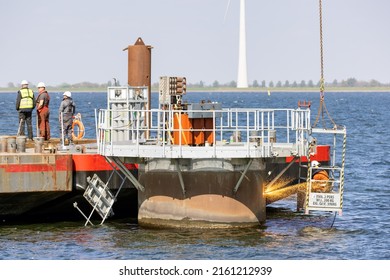 Lelystad, The Netherlands - April 22, 2022: Worker with cutting torch at work by demolition foundation offshore windturbine