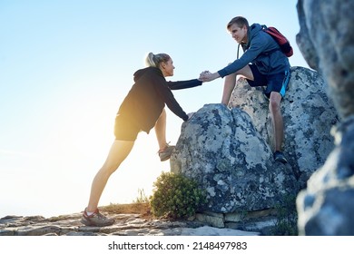 Lemme Give You A Hand. Full Length Shot Of A Young Man Helping His Girlfriend While Hiking.