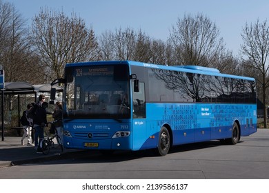 LEMMER, THE NETHERLANDS - MARCH 26, 2022: Blue ARRIVA bus with passengers outside at the station of the Dutch village of Lemmer. Dutch text 'For each other - With each other' on the side of the bus