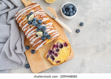 Lemon blueberry cake with lemon icing and fresh berries on top on the board on a gray concrete background with cup of tea. Selective focus. Copy space - Powered by Shutterstock