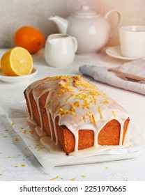 Lemon bread coated with sugar sweet icing and sprinkled with lemon peel. Cake with citrus, poppy, traditional american cuisine. Whole loaf. White background, side view, close up, vertical
