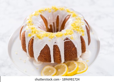 Lemon bundt cake decorated with lemon zest on a cake stand.