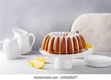 Lemon bundt cake drizzled with powdered sugar glaze on a cake stand