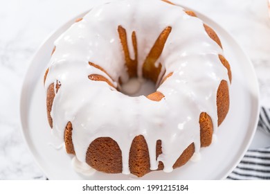 Lemon Bundt Cake Glazed With White Glaze On A Cake Stand.