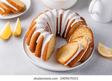 Lemon bundt cake sliced on a plate with powdered sugar glaze drips