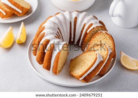 Lemon bundt cake sliced on a plate with powdered sugar glaze drips