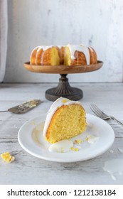 Lemon Bundt Cake With White Glaze On Cake Stand With Cake Slice