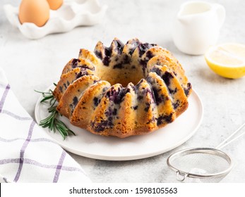 Lemon cake with blueberry decorated with lemon half and rosemary, white background. Breakfast morning table.