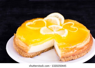 Lemon cheesecake on a black background decorated with lemon zest close-up