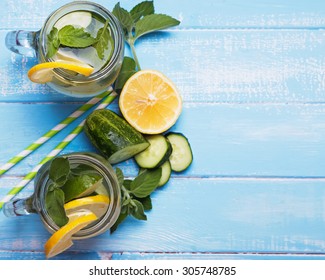 Lemon And Cucumber Detox Water In Glass Jars On Blue Colored Wooden Background, Top View