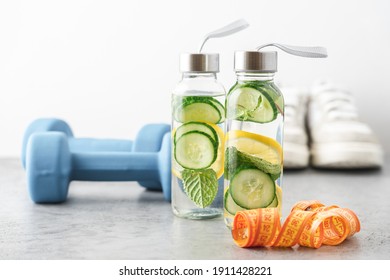 Lemon, cucumber and mint water in glass bottles. Sassy water for detox or dieting with fitness dumbbells in the background. Healthy eating, weight loss,  lifestyle concept