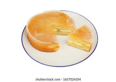 Lemon Drizzle Cake On A Plate With A Slice Cut Out Isolated Against White