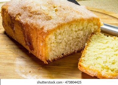 Lemon Drizzle Cake On A Wooden Board With Front Slice