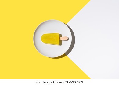 Lemon flavored ice lolly. Ice cream stick on yellow and white background. Top view. summer concept