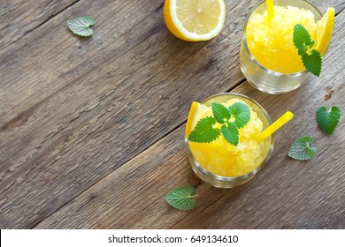 Lemon Frozen Granita Slush Drink In Glasses On Rustic Wooden Table. Homemade Italian Granita Dessert, Refreshing Summer Slush Drink.