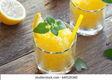 Lemon Frozen Granita Slush Drink In Glasses On Rustic Wooden Table. Homemade Italian Granita Dessert, Refreshing Summer Slush Drink.