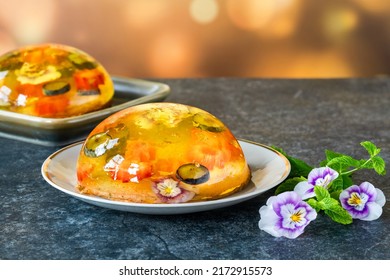 Lemon jelly globes with fresh fruit, edible flowers and gold flakes on pistachio biscuit - gourmet dessert - Shutterstock ID 2172915573