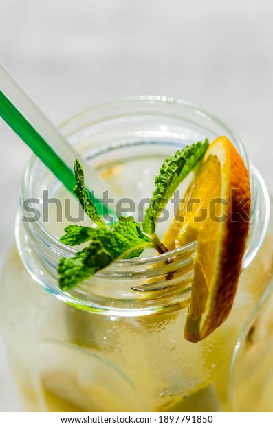 Lemon lemonade in mason jar glass ofwith lemons and\
straw on tab