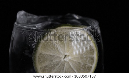 Lemon, lime in a glass with soda water (bubbles), black background.