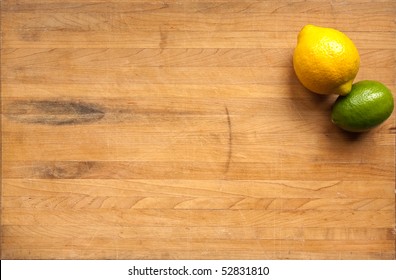 A Lemon And A Lime Sit On A Worn Butcher Block Cutting Board