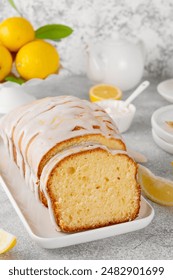 Lemon loaf cake with sugar icing on a white plate on a stone background. Copy space