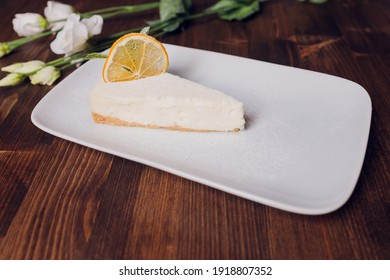 Lemon meringue pie with cup of coffee on white wooden background.