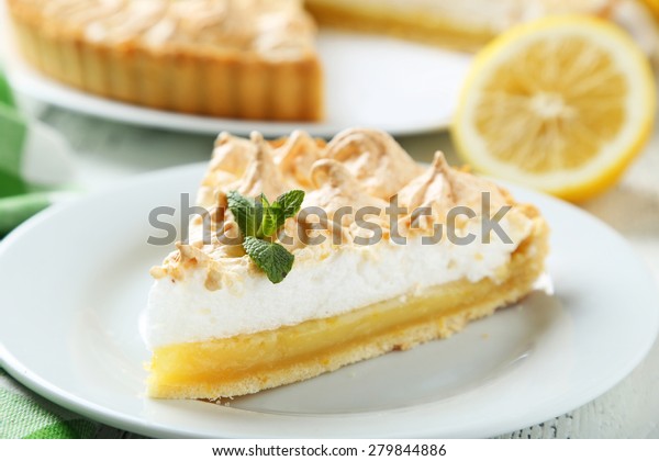 Lemon\
meringue pie on plate on white wooden\
background