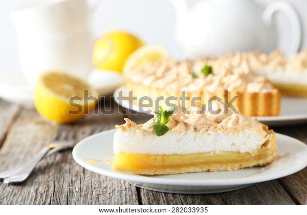 Lemon\
meringue pie on plate on grey wooden\
background