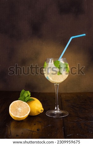 Lemon mint drink. A goblet with a straw. Ice cubes and mint in a glass. Soda with lemon and mint. Mojito. Vertical frame.