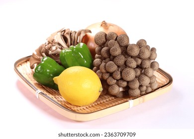 Lemon, mushrooms and vegetables on a bamboo colander on white background - Shutterstock ID 2363709709