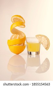 Lemon Peeled Skin And Lemon-flavored Italian Liqueur Limoncello Isolated On Yellow Background.