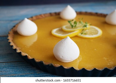 Lemon Pie (tart) With Meringue And Butter Cookie Crust. Blue Wooden Table, Lemon Slices On Top