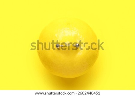 Lemon with piercing on yellow background