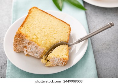 Lemon pound cake baked in a bundt pan sliced topped with powdered sugar, slice on a plate