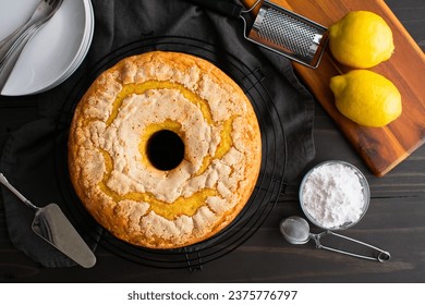 Lemon Pound Cake on a Round Wire Cooling Rack: Pound cake made in a tube pan surrounded by powdered sugar, plates, and more - Powered by Shutterstock