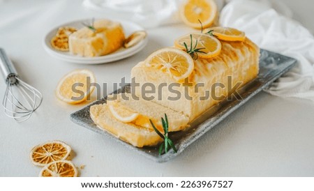Lemon pound cake topped with icing sugar glaze, lemon slices and rosemary close up