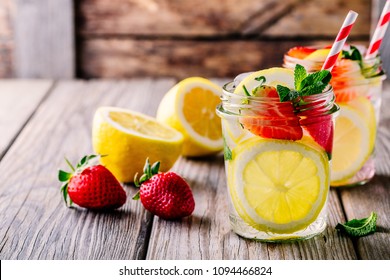 Lemon And Strawberry Lemonade In Glass Mason Jars On A Wooden Background. A Refreshing Summer Drink.