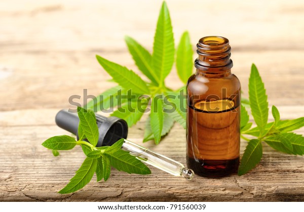Lemon Verbena essential oil and leaves on the\
wooden board