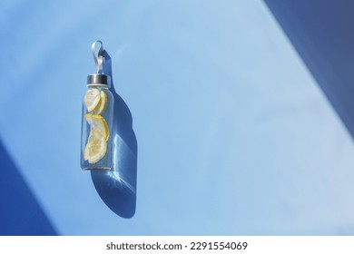 Lemon water drink detox in bottle, hard shadow at sunlight on blue background. Wellness, diet, eating healthy concept. Top view glass reusable water bottle, eco friendly lifestyle, minimal style photo - Shutterstock ID 2291554069
