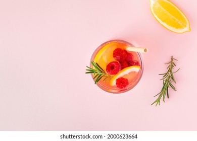 Lemon Water Or Lemonade With Raspberry And Rosemary On A Pink Background, Top View. Aromatic Cool Cocktail For The Summer Heat.